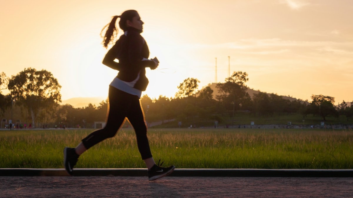 Woman running on track at sunset.